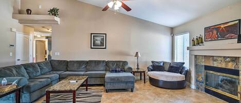 A living room with a sectional sofa, a loveseat, a coffee table, a fireplace, and a ceiling fan.