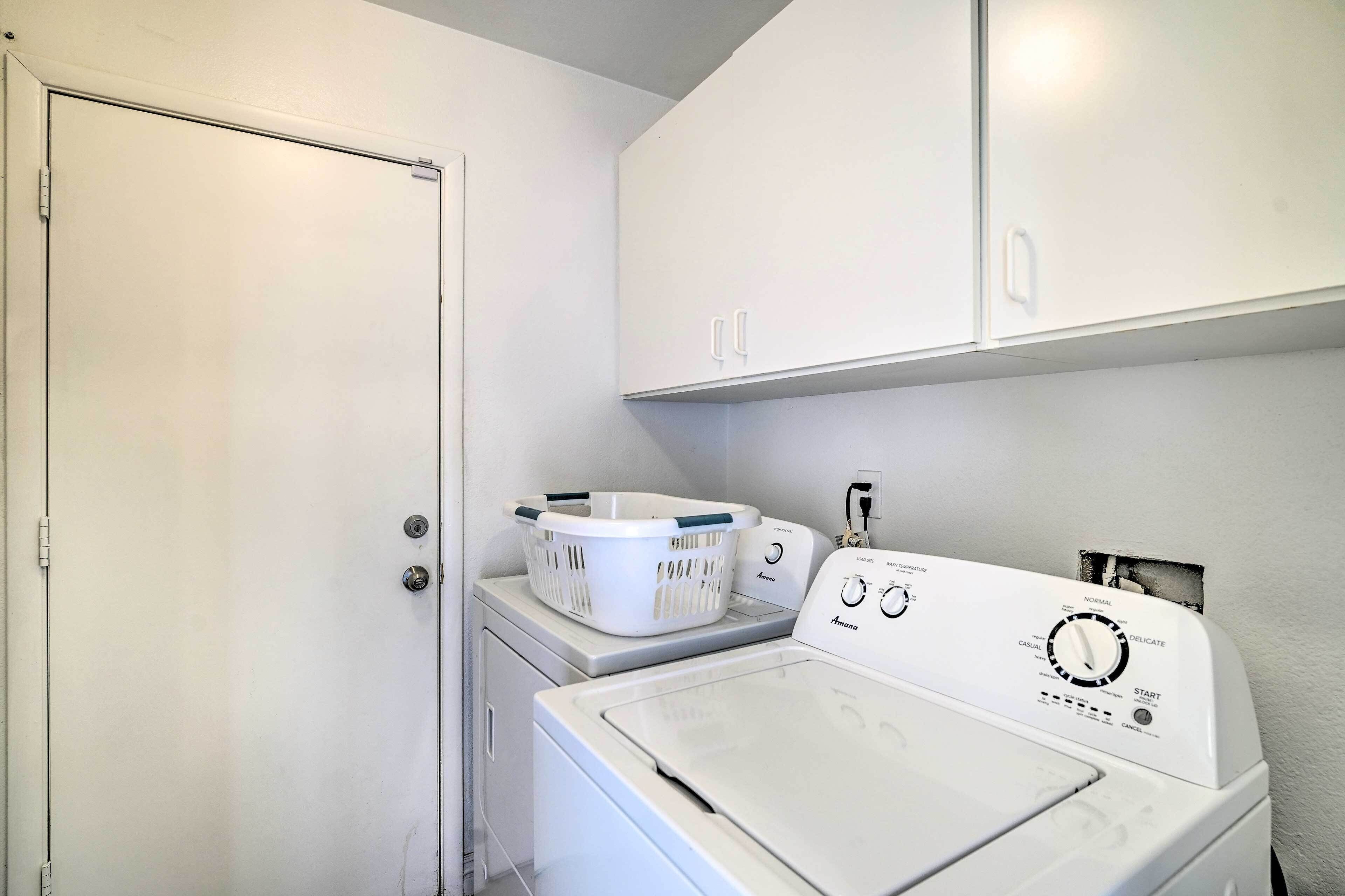 A laundry room with a front-loading washer and dryer, a basket on the dryer, and a door to the room.
