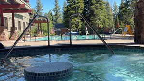 A swimming pool with a tiled hot tub, wooden deck, and surrounding trees. - Northstar Tahoe Summer Resort Condo: Pools, Pickleball, Hike Trails, 2BR 2BA (Truckee)