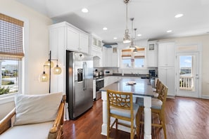 A modern kitchen with white cabinets, stainless steel appliances, and a central island with bar stools. - "Tropical Punch" Tastefully decorated 4 bedroom, 3.5 bathroom home w/ a private pool. (Holden Beach)