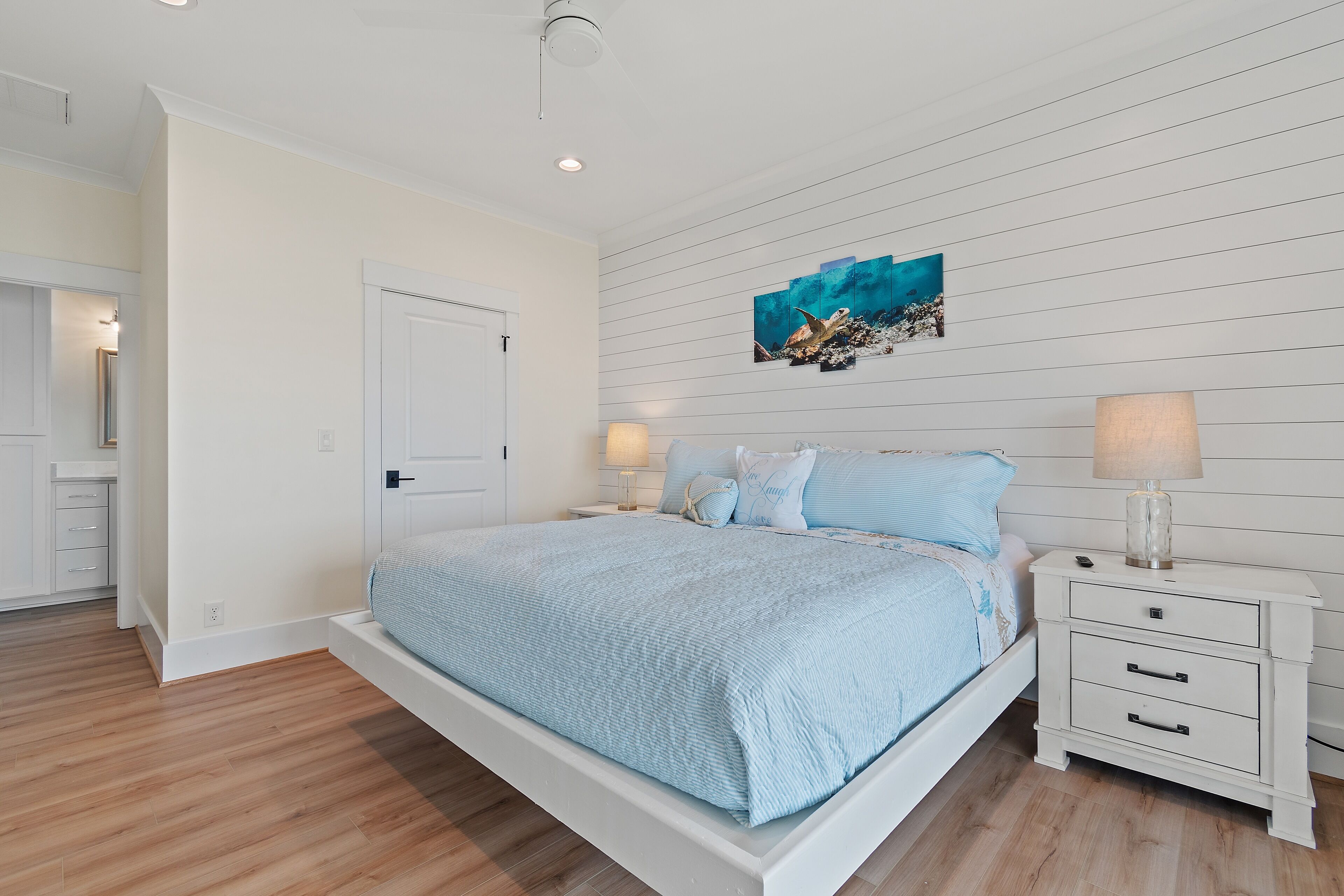 A bedroom with a bed, nightstands, and a wall-mounted artwork.