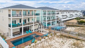 A multi-story hotel with balconies, a pool, and a beach view.