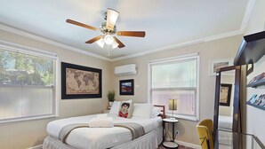 A bedroom with two beds, a ceiling fan, a world map, and a bookshelf.
