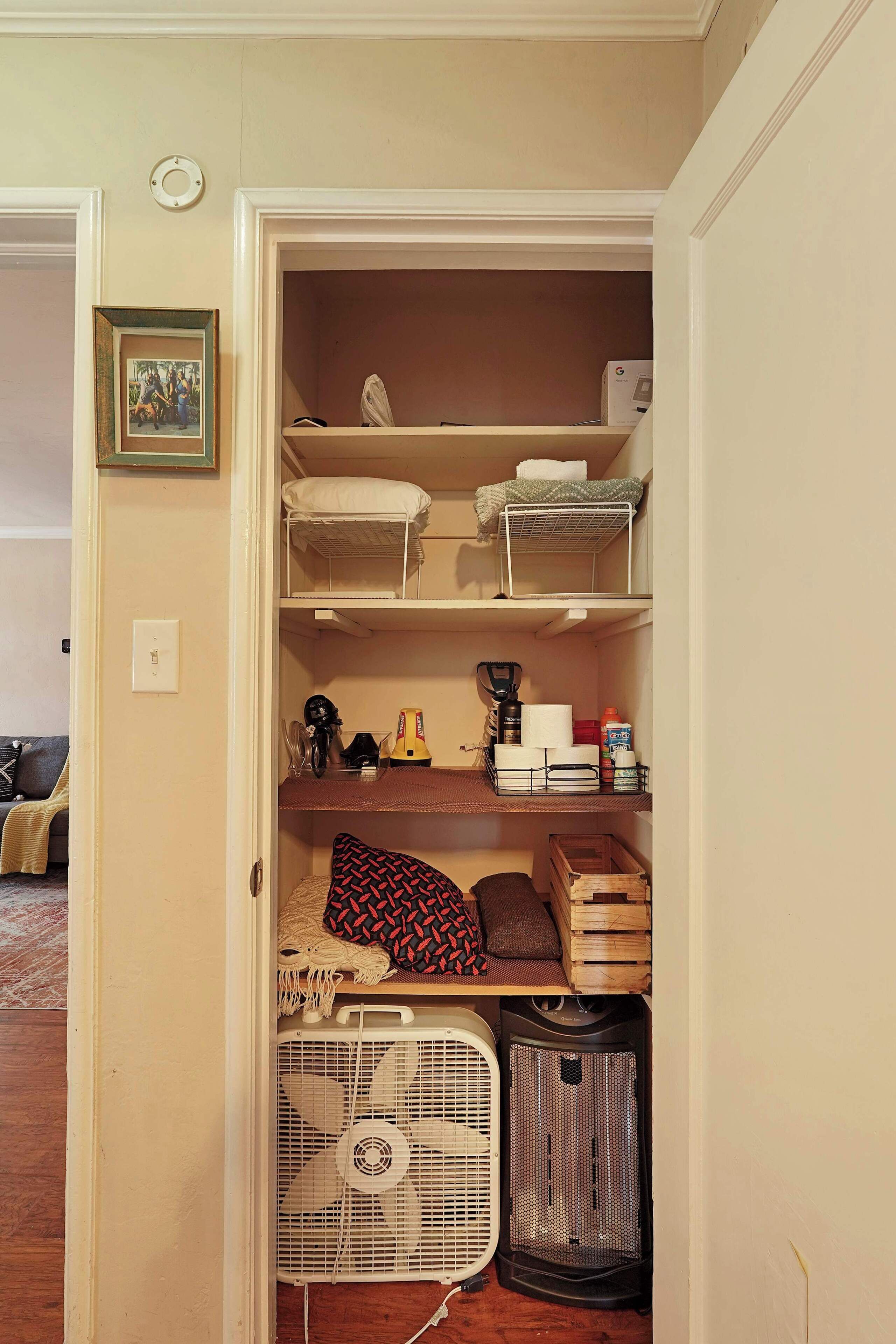 A closet with shelves, a fan, and storage boxes.