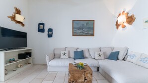 A living room with a white sofa, a wooden coffee table, a TV, and wall-mounted lights. - Villa Soleluna 7+1, Emma Villas (Marina di Marittima)