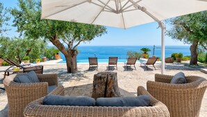 A sunlit outdoor seating area with wicker furniture, a central wooden stump, and an umbrella providing shade. - Villa Soleluna 7+1, Emma Villas (Marina di Marittima)