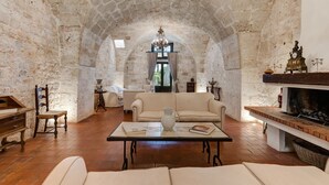 Ein gemütliches Wohnzimmer mit Steinwand, Kamin, Sofa, Couchtisch und einer Deckenleuchte.