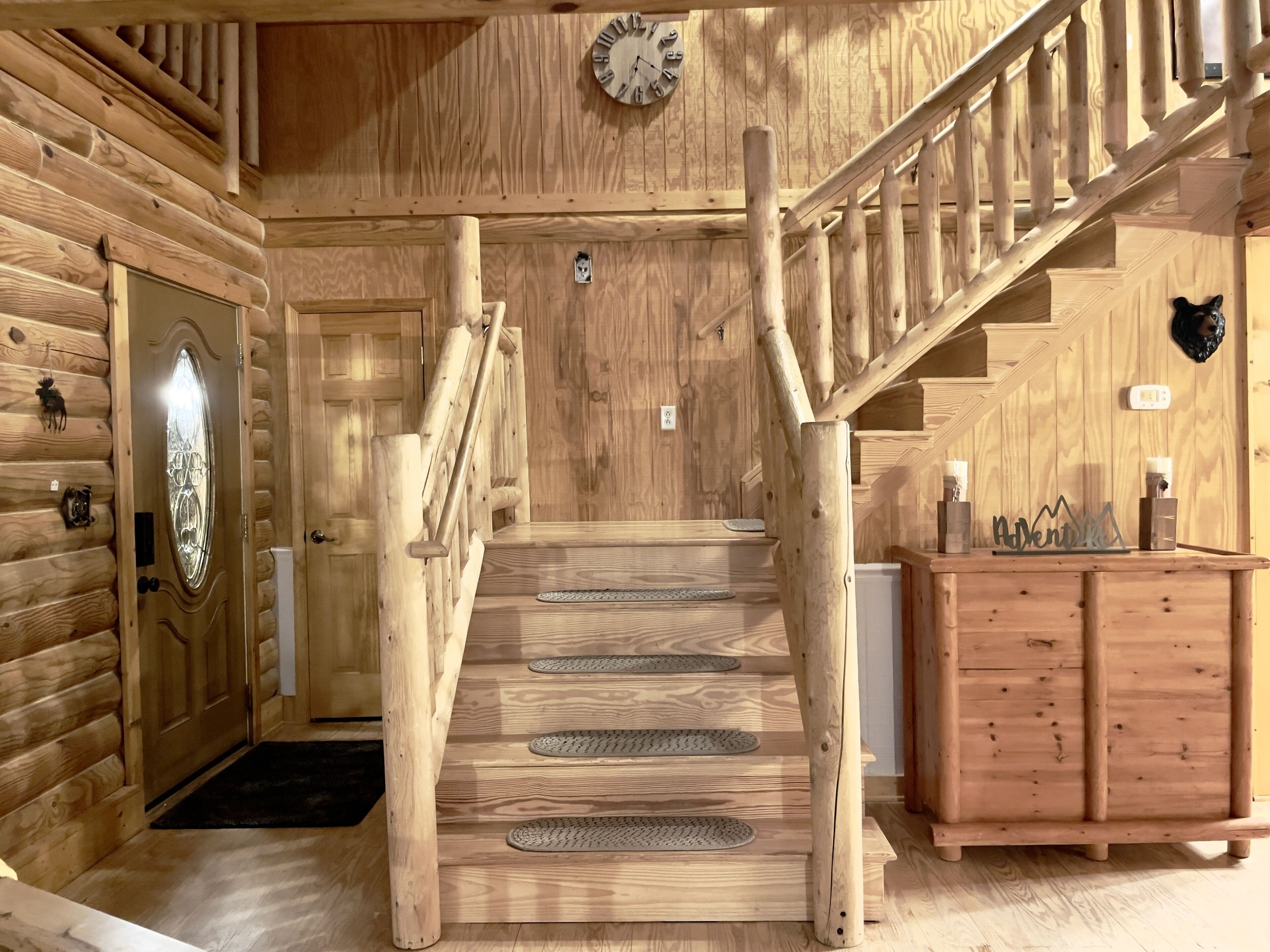 A wooden staircase with a handrail and a wooden wall with a clock.