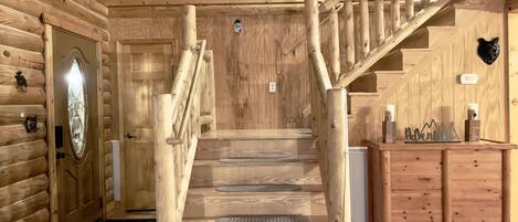 A wooden staircase with a handrail and a wooden wall with a clock.