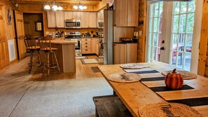 Une cuisine chaleureuse avec des meubles en bois, un îlot central doté de tabourets et une grande fenêtre donnant sur l’extérieur.