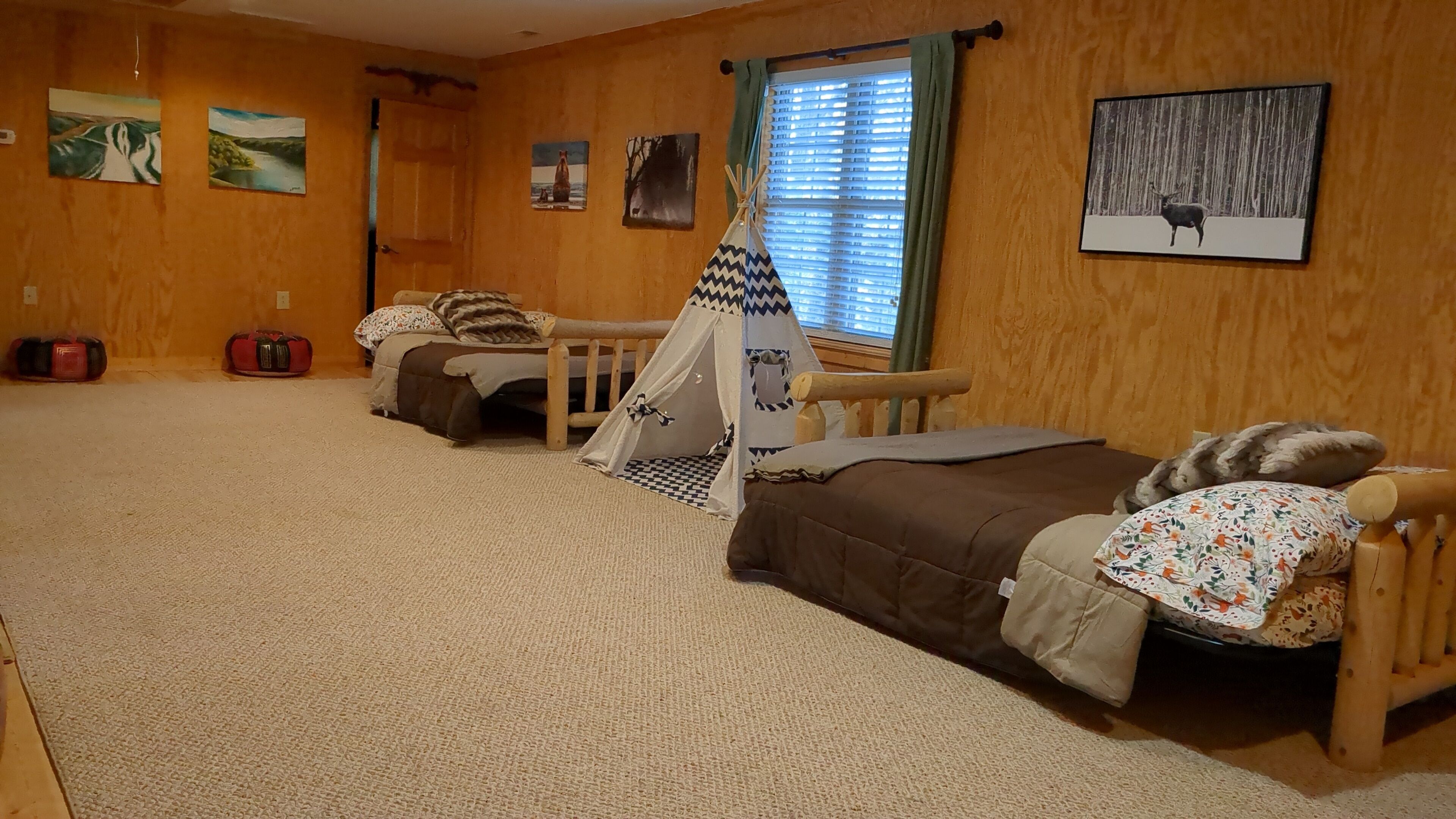 Une chambre confortable avec deux lits, un plancher en bois et une fenêtre équipée de stores.
