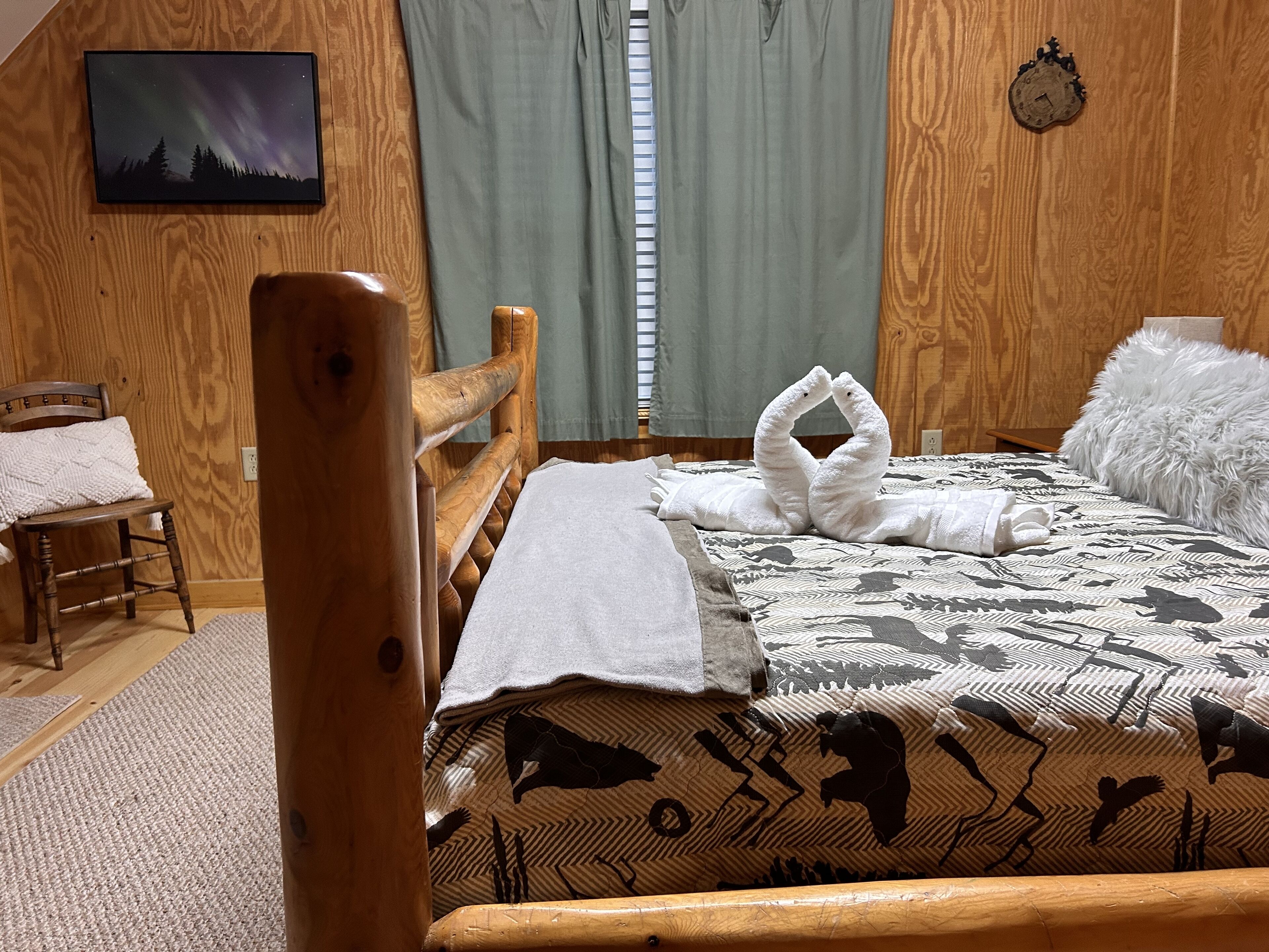 Une pièce chaleureuse avec un lit en bois, une chaise en bois, une petite table et une horloge murale.