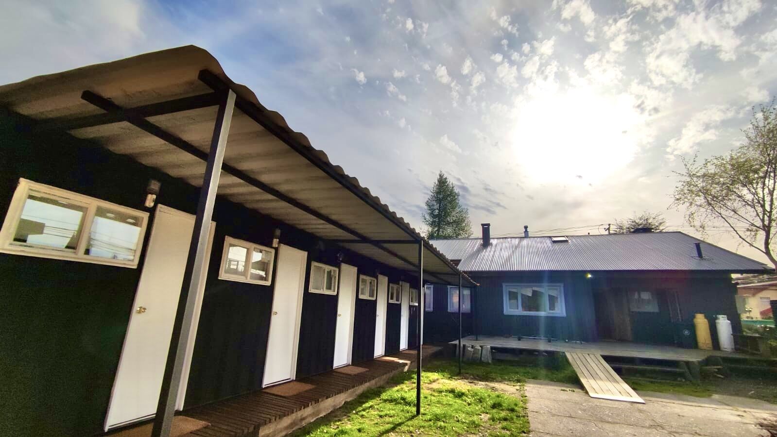A single-story building with a dark exterior and a covered porch. There are multiple doors and windows, and a small deck area.