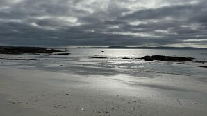 Une plage avec un ciel nuageux, mais où le soleil perce à travers les nuages.