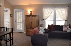 Relax in this inviting living room with a sofa, dining table, and wooden cabinet.