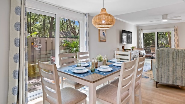 A dining area with a table set for four, wooden chairs, and a hanging light fixture.