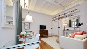 Een moderne woonkamer met een glazen eettafel, een witte bank en een televisie.