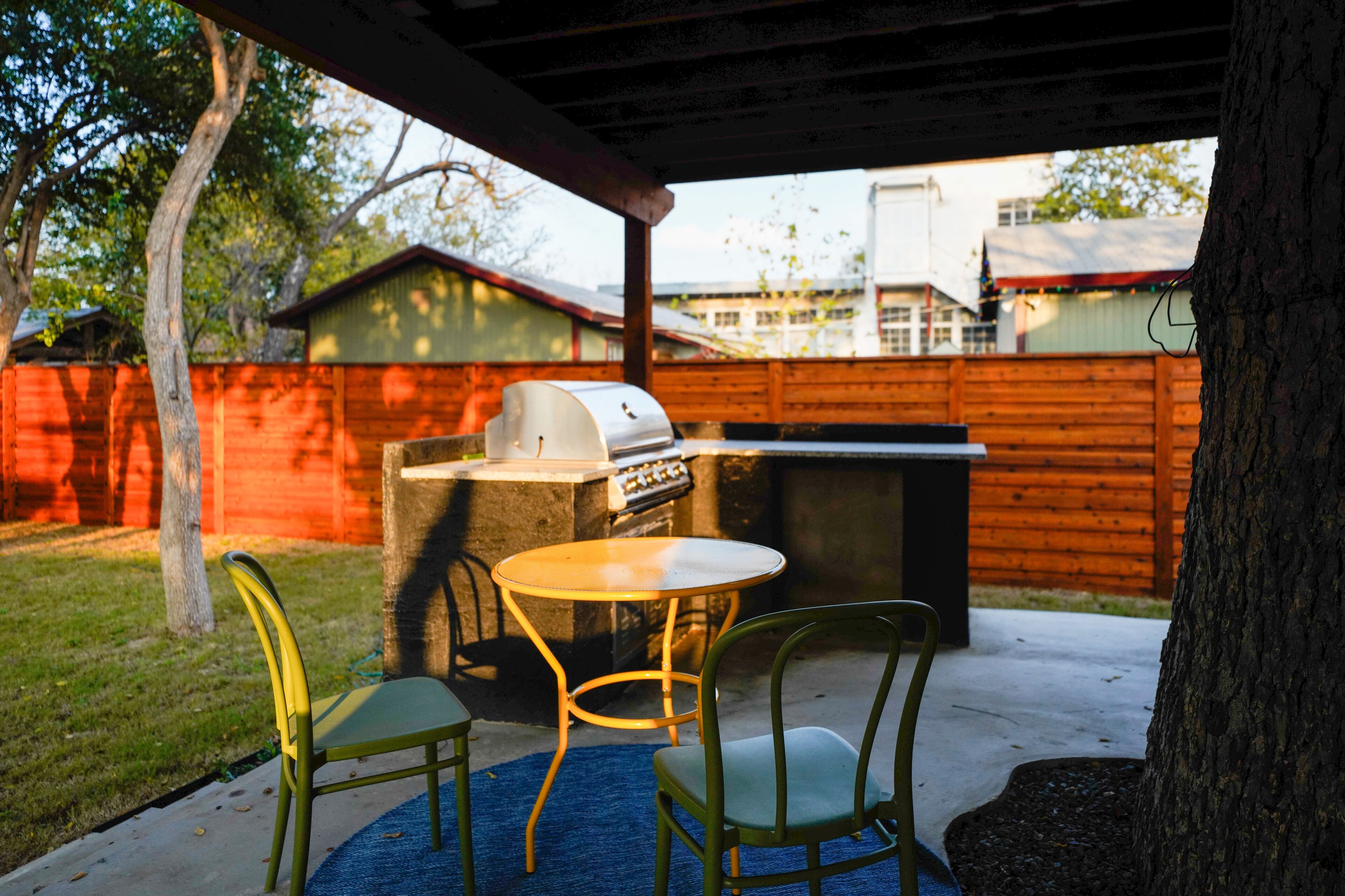 An outdoor patio with a grill, two chairs, and a table.