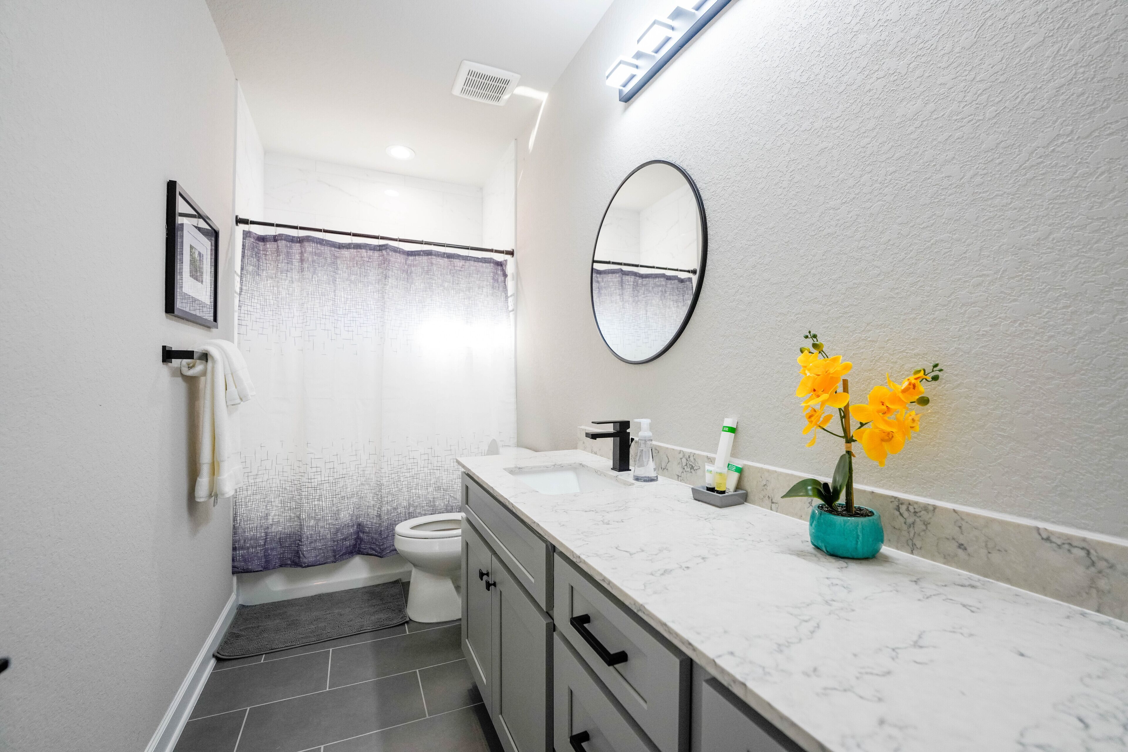 Un baño moderno con un lavamanos blanco, un espejo y una cortina de ducha.