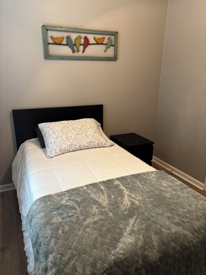 A bedroom with a bed, a nightstand, a wall-mounted artwork of birds, and a patterned pillow. - Country Cottage with a Lake View- First Monday Nearby (Edgewood)
