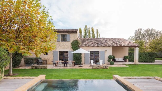 Una casa con piscina, mobiliario de exterior y un jardín bien cuidado.