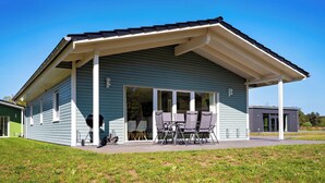 Une maison de plain-pied dotée d’un patio couvert, d’un barbecue et de meubles d’extérieur.