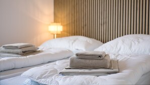 Un lit bien fait, avec des serviettes pliées et une lampe en arrière-plan.