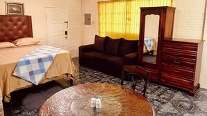 Una habitación con cama, sofá, cómoda y mesa redonda.