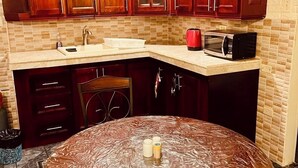 Una cocina con armarios de madera, microondas y lavamanos.