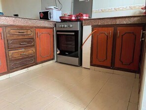 A kitchen with wooden cabinets, a microwave, and an oven.