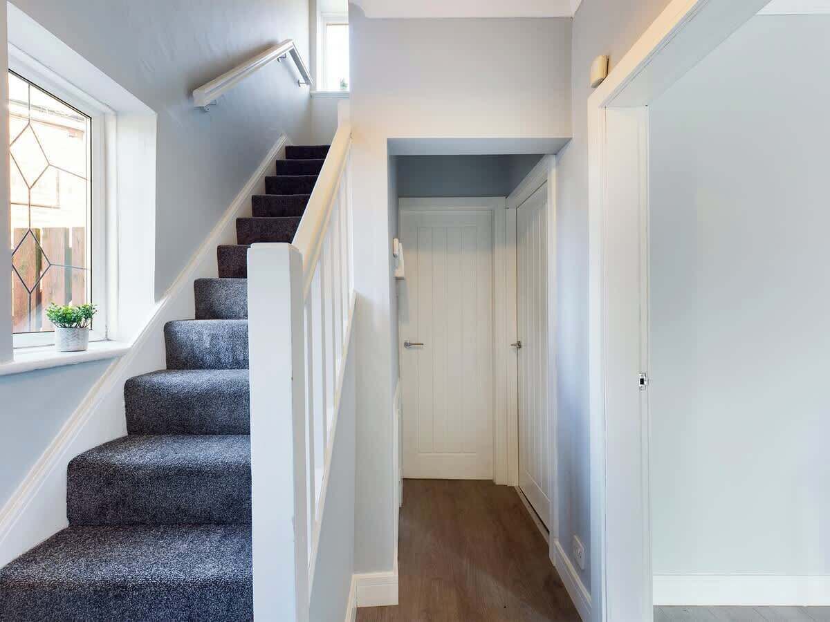 A staircase leading to a door, a window with a plant, and a hallway with a door.