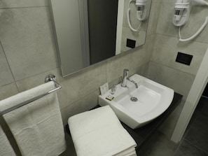 A bathroom with a white sink, a mirror, and a towel rack. - Erasmus Hotel (Gela)