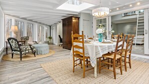 A dining area with a table set for six, surrounded by wooden chairs, a chandelier, and a large window. - Guilford Carriage House at Granite Lodge! (Guilford)