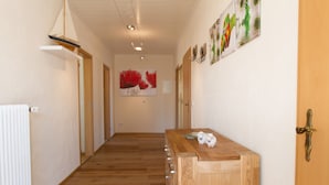 Un couloir doté d’un plancher en bois, d’un comptoir d’accueil en bois et d’une porte avec une poignée en laiton.