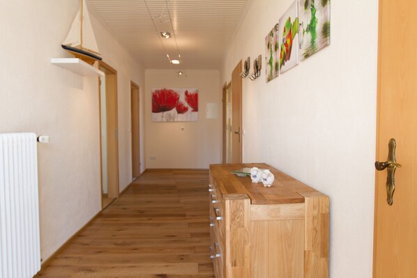 Un couloir doté d’un plancher en bois, d’un comptoir d’accueil en bois et d’une porte avec une poignée en laiton.