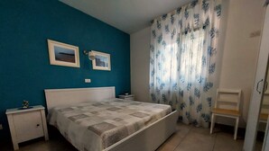 Ein Schlafzimmer mit Bett, Nachttischen, einem Sessel und einem Fenster mit Vorhängen.