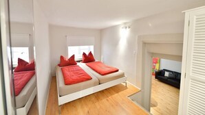 Ein modernes Schlafzimmer mit einem Bett, roten Kissen und einem weißen Kopfteil.