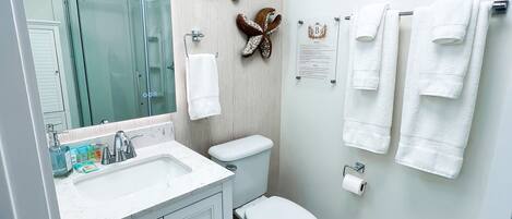 A modern bathroom with a glass shower enclosure, a white toilet, and a marble-patterned floor.