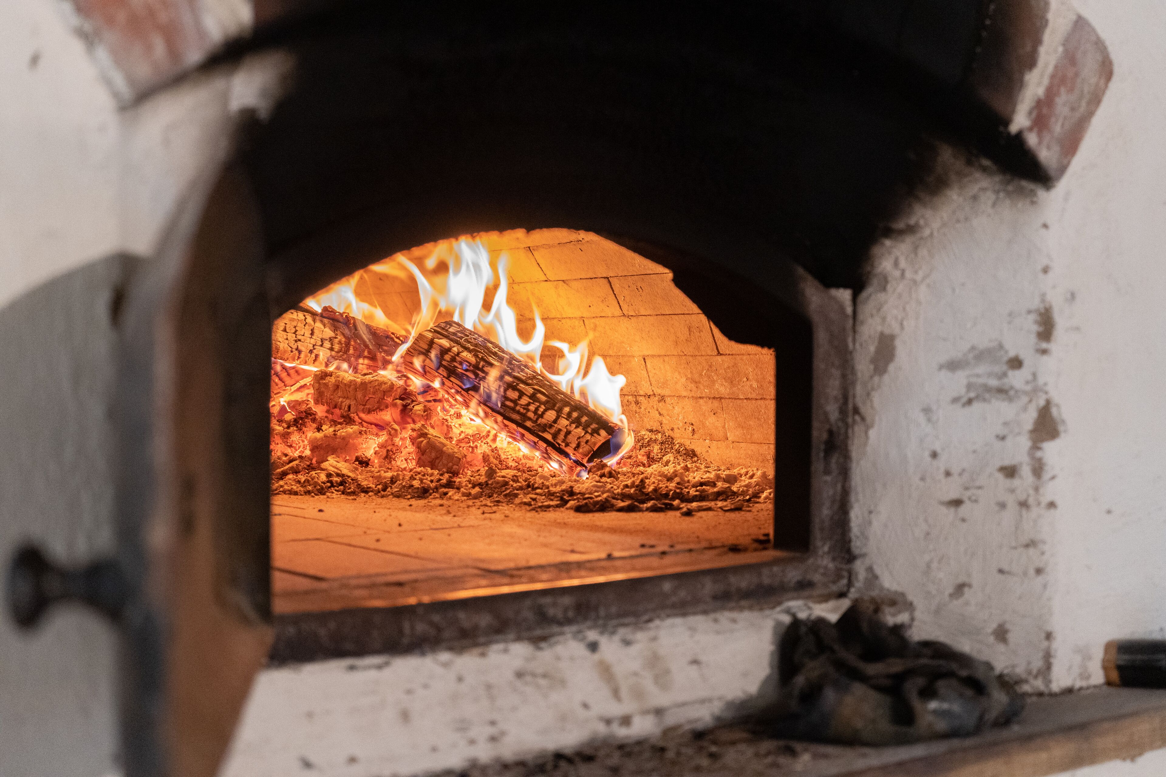A wood-fired oven with visible flames and firewood inside.