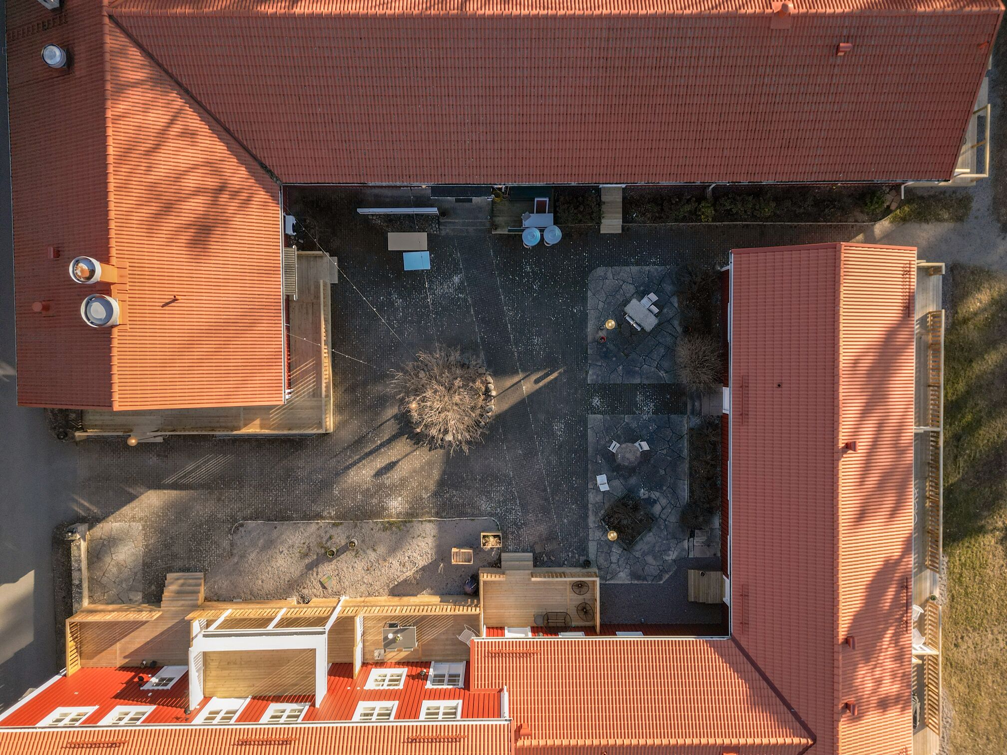 An aerial view of a building with a red roof, a courtyard with seating, and a small garden area.