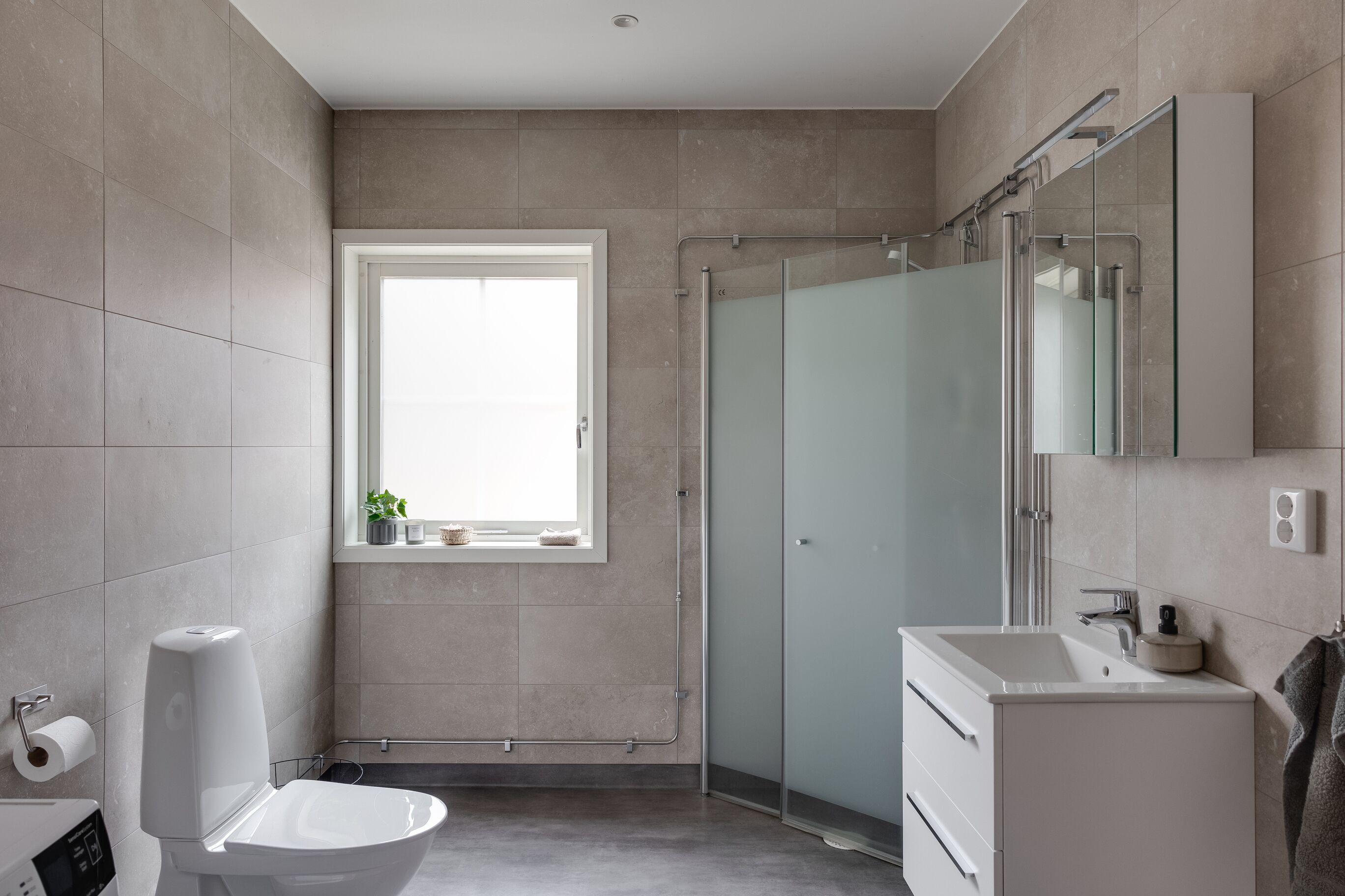 Un baño moderno con inodoro, lavamanos y ducha.