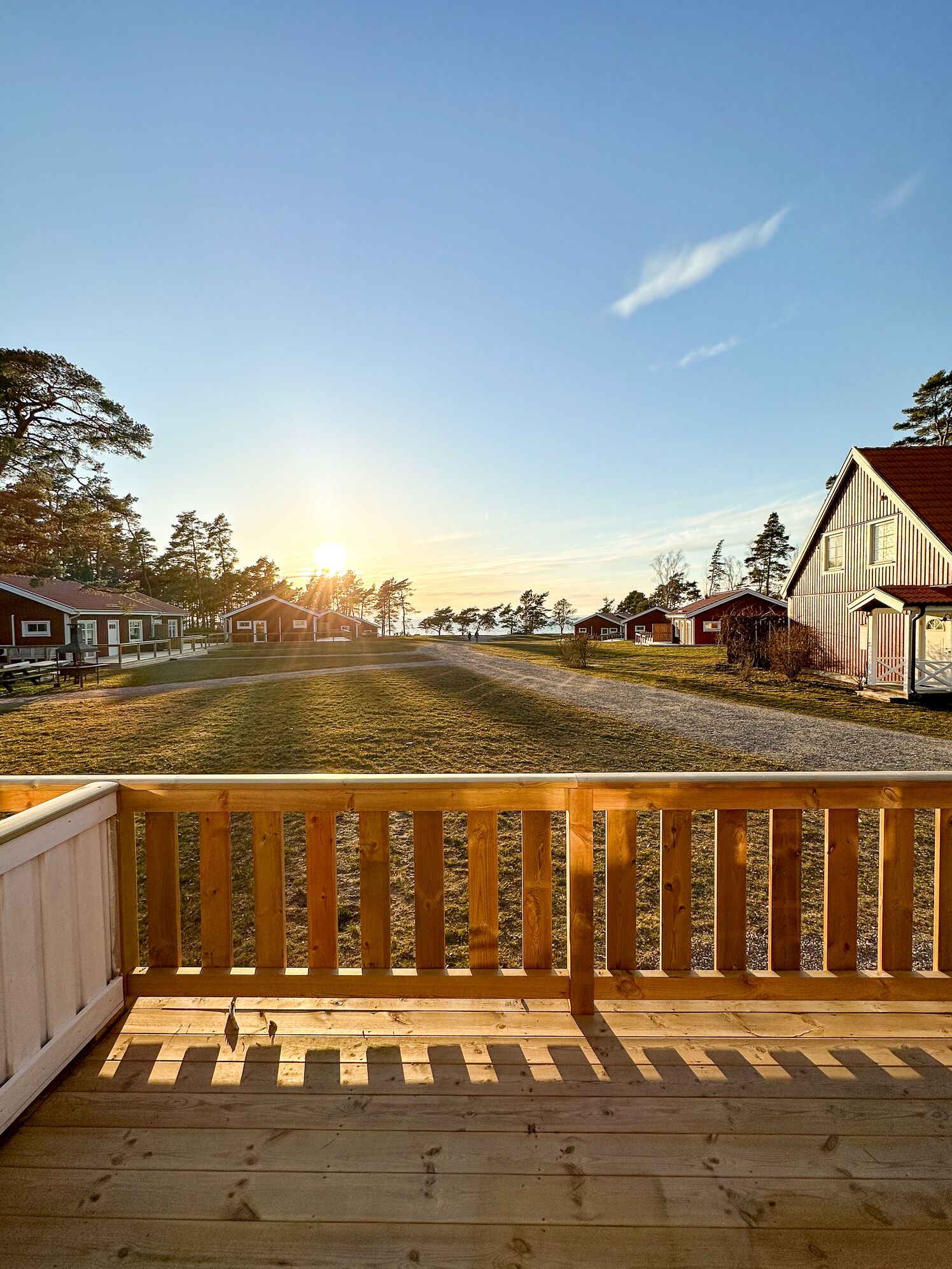 A wooden deck with a railing, a clear sky, and a view of a residential area with houses and trees.