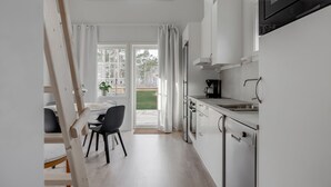 A modern kitchen with a skylight, a dining area with a table and chairs, and a view of the outdoors. - Stora Frögården (Morbylanga)