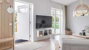 A modern living room with a flat-screen TV, wooden flooring, and large windows. - Stora Frögården (Morbylanga)