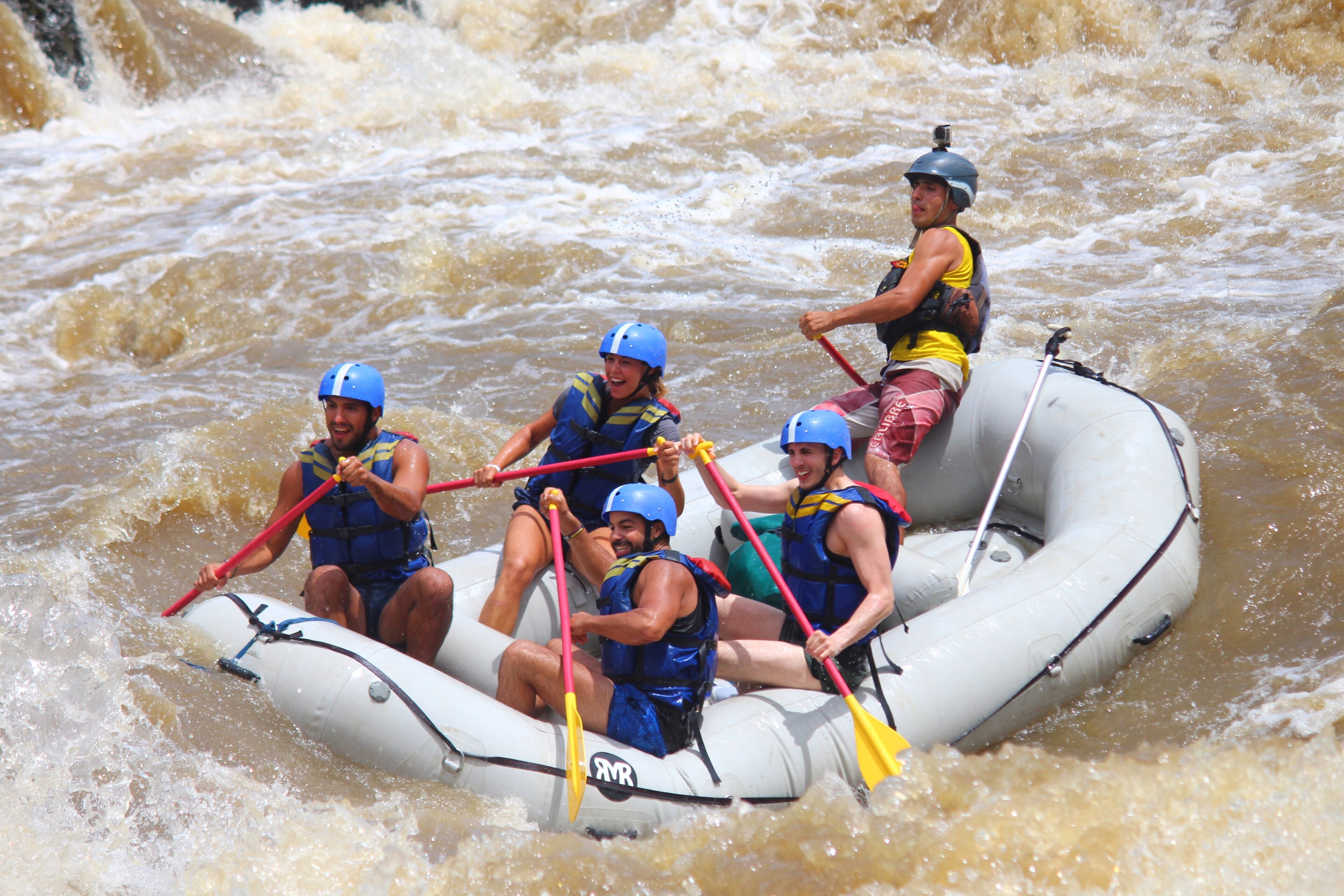Un grupo de personas en un bote inflable blanco navega por un río con rápidos.