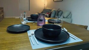 A dining table set with black plates, bowls, and cutlery, with a glass of water and a candle holder. - Lavender home: King & Queen (Edinburg)