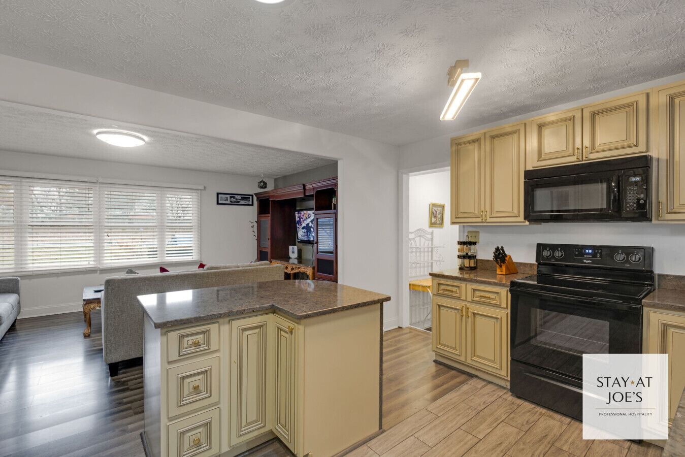 A modern kitchen with wooden cabinets, a black microwave, and a built-in oven.
