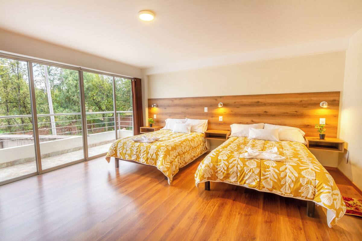 Ein Hotelzimmer mit zwei Betten, großen Fenstern und einem Balkon.