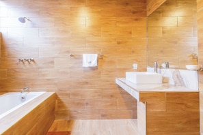 A modern bathroom with a wooden floor and walls, a freestanding bathtub, a sink with a marble countertop, and a towel rack.