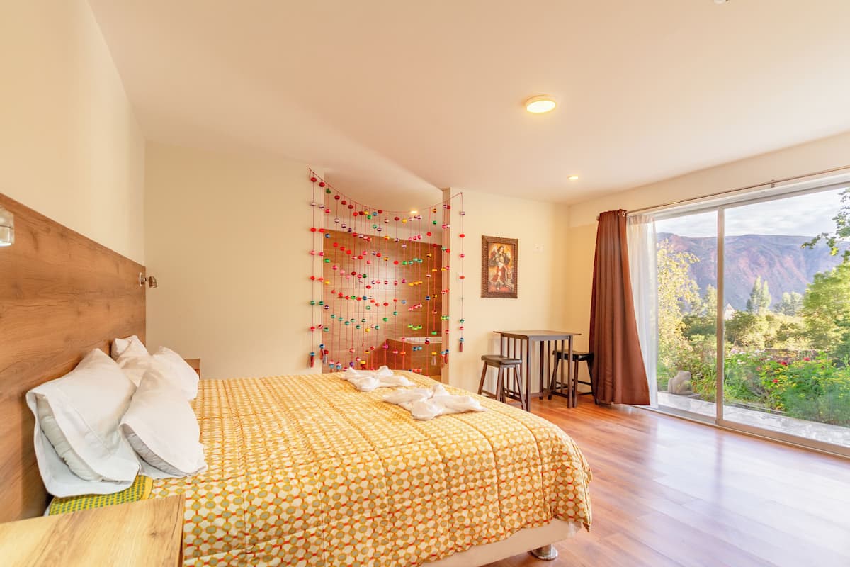 Ein Schlafzimmer mit einem Bett, einem Schreibtisch und einem großen Fenster mit Bergblick.
